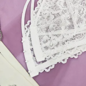 Gros plan de bralette en dentelle blanche avec motif floral délicat et fermeture à crochets.