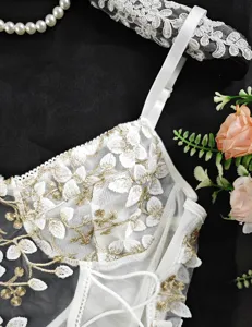 Body in pizzo sexy trasparente ricamato con dettagli floreali dorati e coulisse in vita.