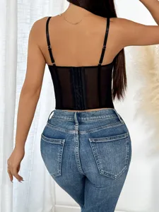 Back view detail of a black mesh corset top featuring thin adjustable straps and denim pants.