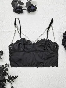 Λεπτομέρεια μαύρου δαντελωτού crop top με τιράντες από στρας και φινίρισμα από δαντέλα.