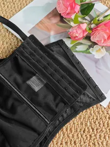 Gedetailleerd overzicht van zwarte mesh corset top met veilige haaksluiting en intern label.