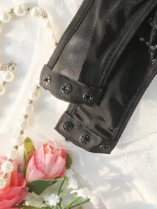 Close-up detail shot of the black lace bodysuit snap button strap, elegant fabric texture.