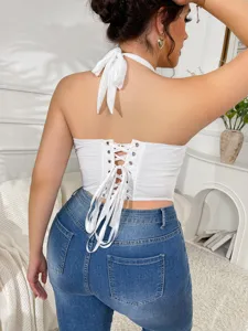 White halter backless lace-up corset crop top paired with stylish blue jeans for women.