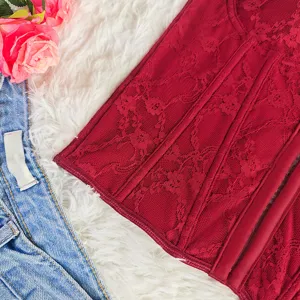 Red lace corset top detail showcasing intricate floral embroidery, underwire, and boned structure.