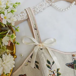 Primer plano detalle de tirante jacquard floral vintage y lazo de satén elegante.