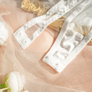 Close up view of white lace bodysuit detail featuring snap button closure and sheer mesh.