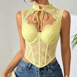 Primo piano del top corset in pizzo giallo con eleganti motivi floreali e lacci delicati.