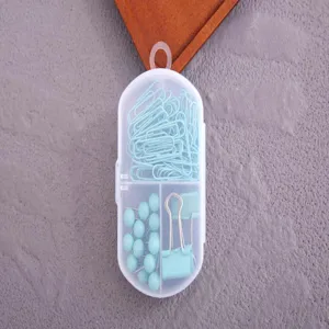 Joli ensemble de trombones punaises pinces bleu pastel dans une boîte de rangement transparente.
