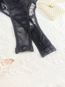 Detailed shot of black lace bodysuit crotch with snap buttons and sheer mesh fabric.