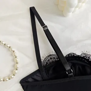 Close-up detail of black lace camisole strap, adjustable metal ring, elegant floral lace.