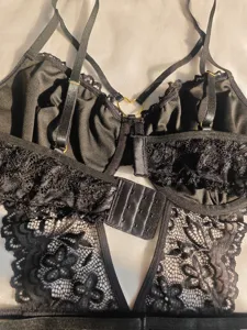 Detailed shot of black sexy lace teddy bodysuit with underwire, strappy design and heart ring.