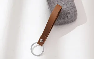 Bruine lederen band sleutelhanger met metalen ring voor autosleutels, gedetailleerde weergave.