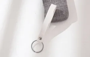 Gedetailleerd overzicht van witte leren sleutelhanger, minimalistische stijl met ring en drukknoop.