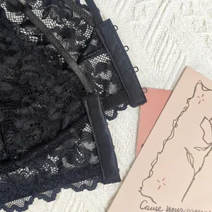 Vue détaillée d'un haut de lingerie en dentelle noire, avec dentelle florale et fines bretelles.
