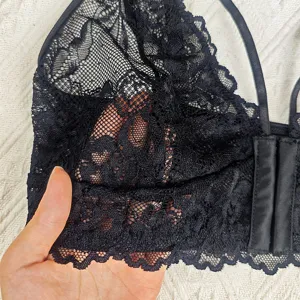 Gros plan sur la texture de la bralette en dentelle noire, tissu transparent aux fines bretelles.