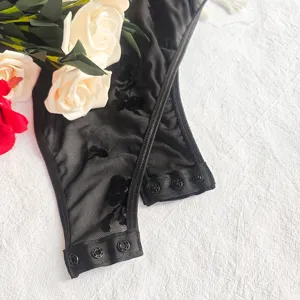 Zwarte mesh bodysuit met geborduurd bloemenpatroon, drukknopen en transparante stof.