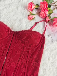 Red lace corset top detail showcasing intricate floral jacquard fabric and structured boning.