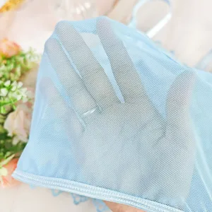 Detaillierte Nahaufnahme von hellblauem, transparentem Netztoff mit zarter Spitzenborte.