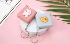Primer plano de mini cinta metrica portatil con pegatina bonita y llavero para uso diario.