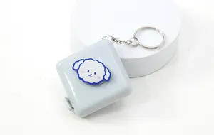 Detalle de la mini cinta métrica portátil en diseño cuadrado gris con un práctico llavero.