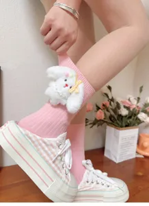 Close-up detail of cute pink mid-calf socks featuring a fluffy white rabbit plush and bow.