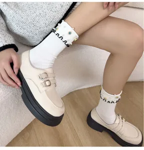 Detailed shot of cute women's white mid-calf socks with pearls, blue rhinestones and ruffles.