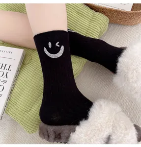 Close-up detail of black ribbed mid-calf socks featuring sparkling rhinestone smiley face.