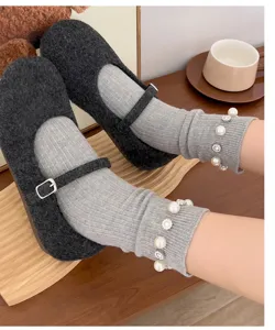 Vue rapprochée détaillée de chaussettes côtelées grises avec perles et chaussures sombres.