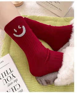 Detail shot of red ribbed mid-calf socks featuring sparkling rhinestone smiley face design.