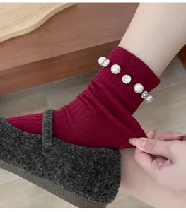 Gros plan de chaussettes en tricot rouge foncé avec des perles et des strass étincelants.
