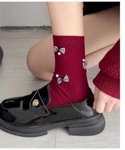 Sweet red mid-calf socks featuring chic plaid bows and pearl decor, paired with classy shoes.