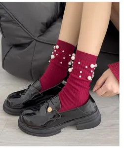 Close-up detail of burgundy ribbed mid-tube socks with elegant pearl embellishments.