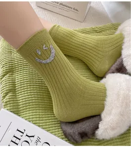 Green ribbed mid-calf socks featuring sparkling rhinestone smiley face, cozy winter knitwear.