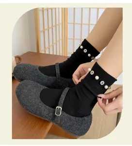 Detail shot of women's black socks with pearls and rhinestones paired with grey flat shoes.