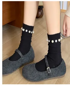 Gros plan de chaussettes montantes noires à côtes ornées de perles élégantes et de strass.