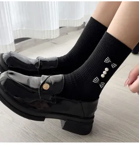 Detailed shot of black women's mid-calf socks featuring plaid bows and pearls, paired with shoes.
