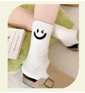 Detailed view of white vertical striped mid-tube socks featuring a cute sparkling winking smiley face.