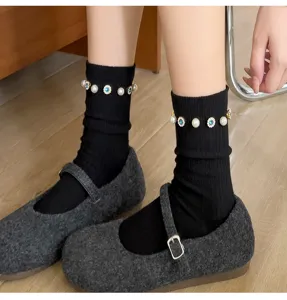 Close-up of black ribbed fashion socks featuring elegant pearl and blue crystal flower charms.