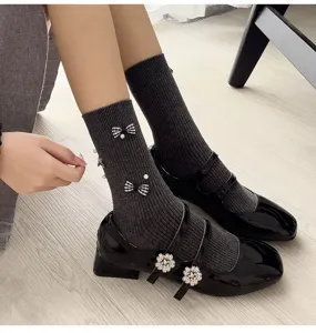 Close-up of stylish dark grey mid-calf socks with plaid bows and chic Mary Jane shoes.