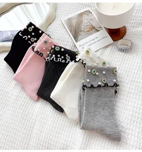Detailed view of women's ribbed mid-tube socks with pearls, blue rhinestones and ruffles.