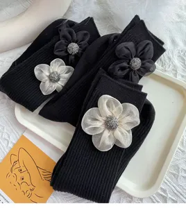 Close-up detail of black ribbed crew socks featuring elegant 3d fabric flower decorations.