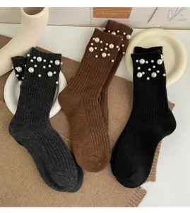 Close-up detail of knitted winter socks featuring elegant faux pearl cuffs and warm wool blend.