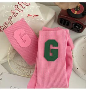 Gros plan sur des chaussettes roses style collégien avec écussons lettre G et tissu doux.