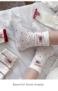 Close up of cute white mid-calf socks featuring red polka dots, delicate lace, and button details.