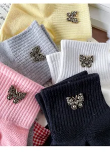 Close-up of cute cotton socks featuring sparkly rhinestone butterfly charms and ribbed cuffs.