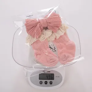 Grazioso set fascia e calzini in maglia per neonata rosa con pizzo, morbido materiale, dettaglio.