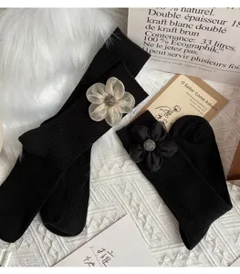 Detail view of black mid-tube cotton socks featuring elegant 3d mesh flower decorations.