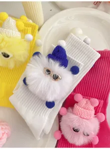 Close up of cute toddler mid tube socks with fluffy elf doll and tiny knit hat detail.