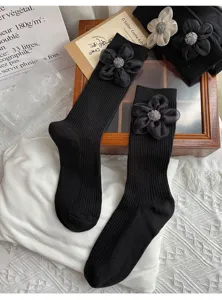 Detailed view of women black mid-tube socks featuring elegant 3d fabric flower and sparkling rhinestones.