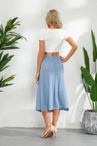 Dettagli della elegante gonna midi blu con top corto bianco, vista posteriore in studio chic.